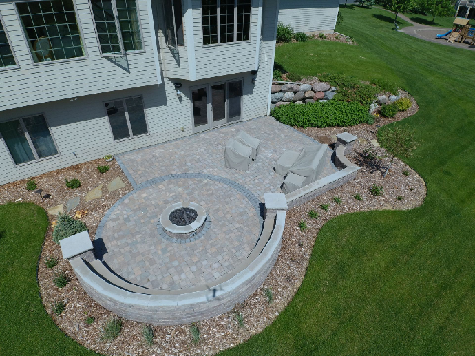 backyard patio featuring a custom built fire pit, seating area, and well-landscaped garden