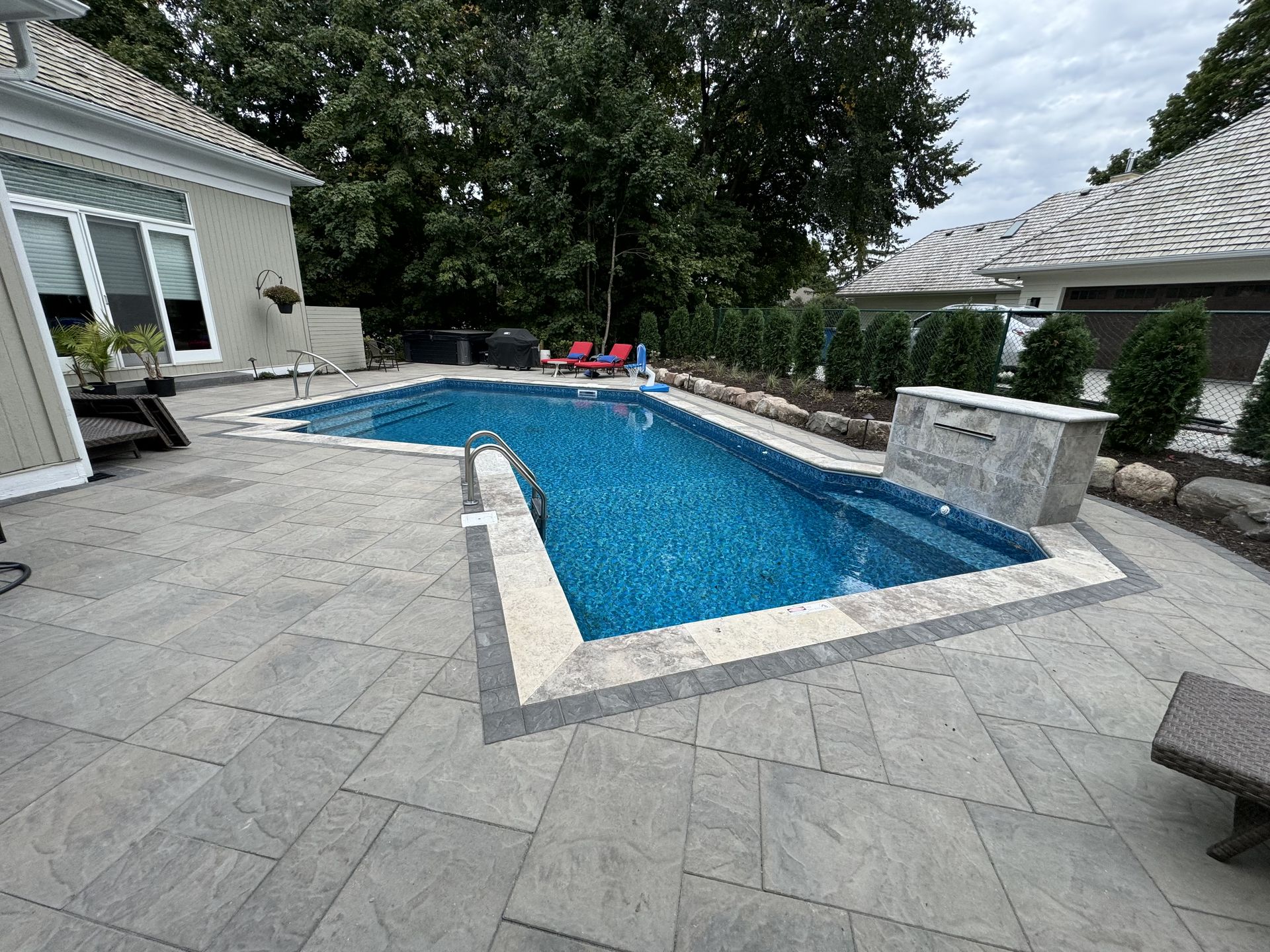 A beautifully designed custom pool featuring surrounding natural stone pavers, blending luxury with function in a serene outdoor space.