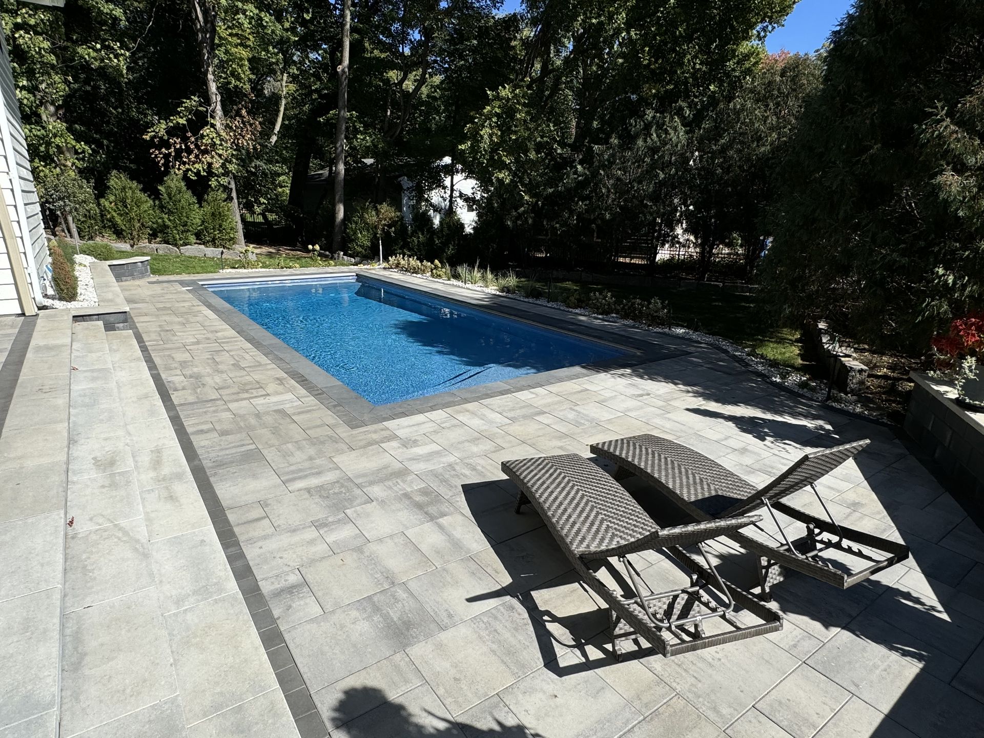 A beautifully designed custom pool featuring surrounding natural stone pavers, blending luxury with function in a serene outdoor space.