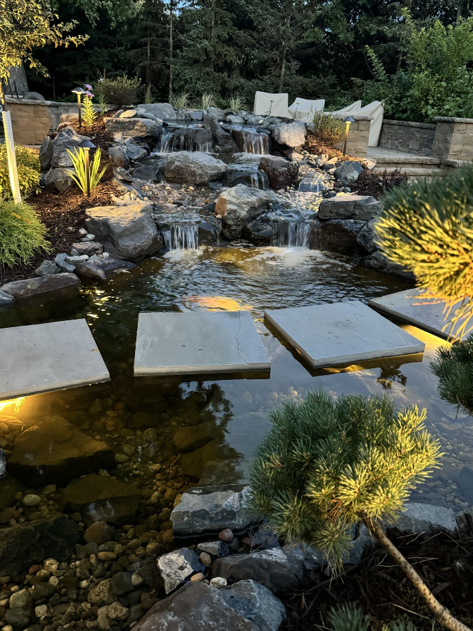 A calming water feature surrounded by a carefully crafted stone pathway, adding an element of tranquility to this beautifully landscaped garden.