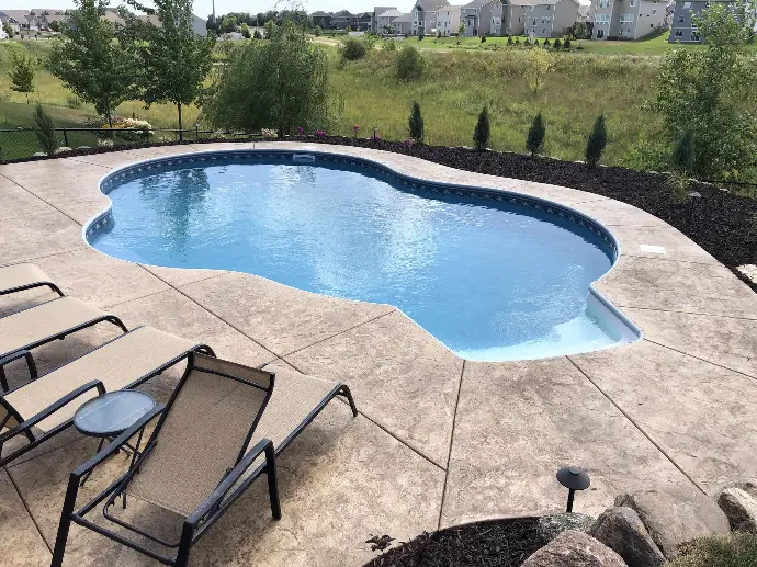 A beautifully designed custom pool featuring surrounding natural stone pavers, blending luxury with function in a serene outdoor space.