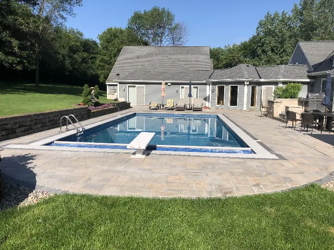 A beautifully designed custom pool featuring surrounding natural stone pavers, blending luxury with function in a serene outdoor space.