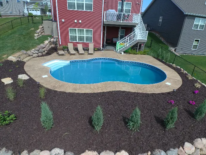 A beautifully designed custom pool surrounded by gorgeous landscaping that perfectly complements this two-story red home.