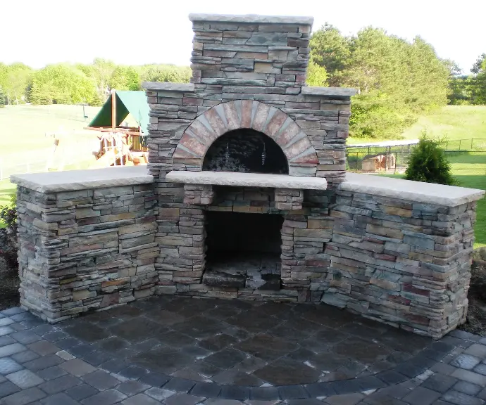 A brick outdoor fireplace with a pizza oven and chimney, creating a traditional and elegant centerpiece for the patio.