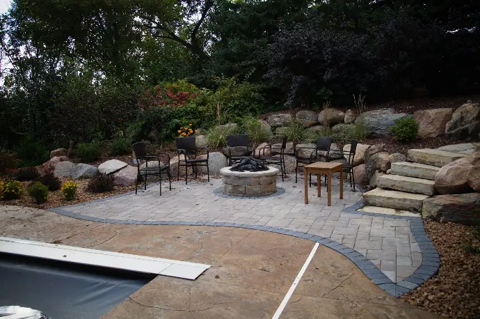 A circular stone fire pit surrounded by pavers, providing a durable and attractive area for outdoor fires.