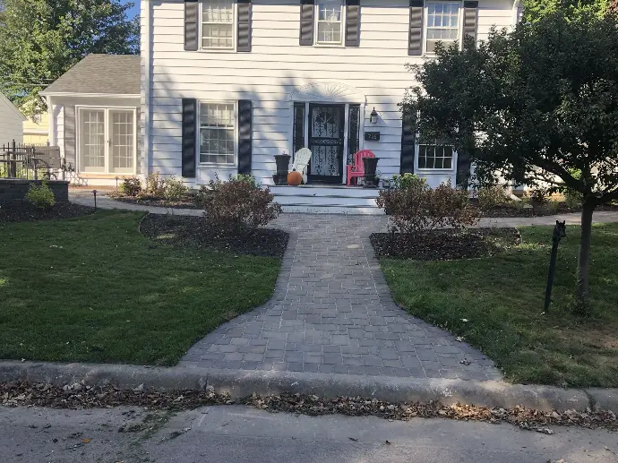 A wide natural stone paver walkway leading to the front door, creating a welcoming entrance.