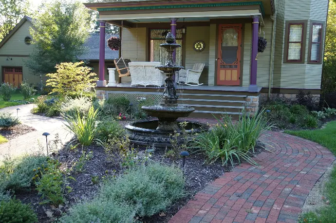 A gently curved natural stone paver walkway winding through a beautifully landscaped garden.