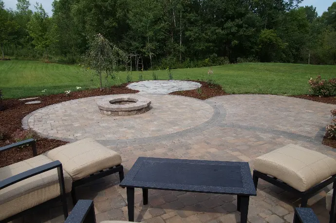 A custom-built stone paver patio centered around a built-in fire pit, creating a cozy outdoor gathering space.