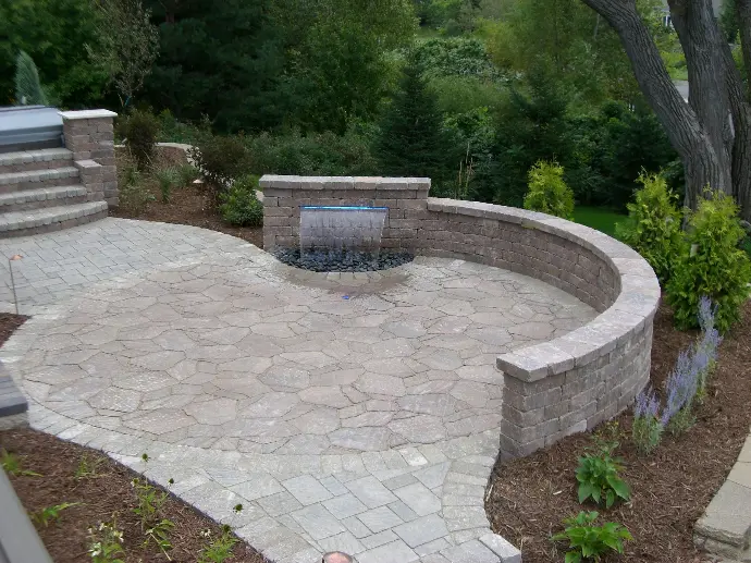 A serene natural stone patio complemented by a calming water feature, perfect for a peaceful outdoor escape.