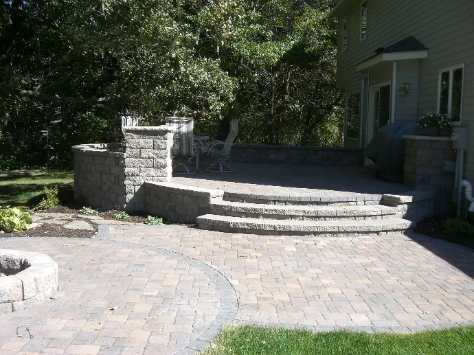 A custom-built stone paver patio centered around a built-in fire pit, creating a cozy outdoor gathering space.