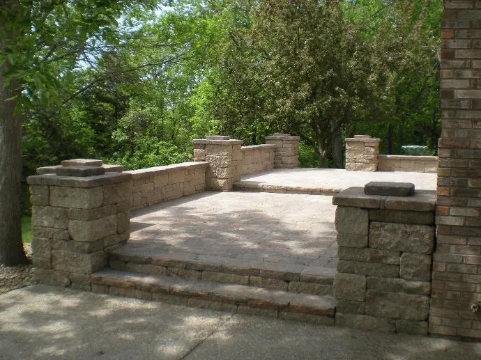 A custom-designed stone paver patio featuring a stylish retaining wall for added structure and appeal.