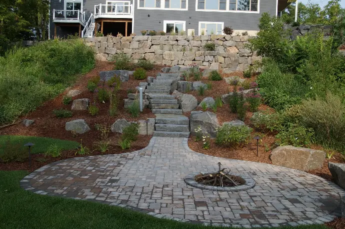 Curved tiered retaining wall with stair walkway leading to fire pit