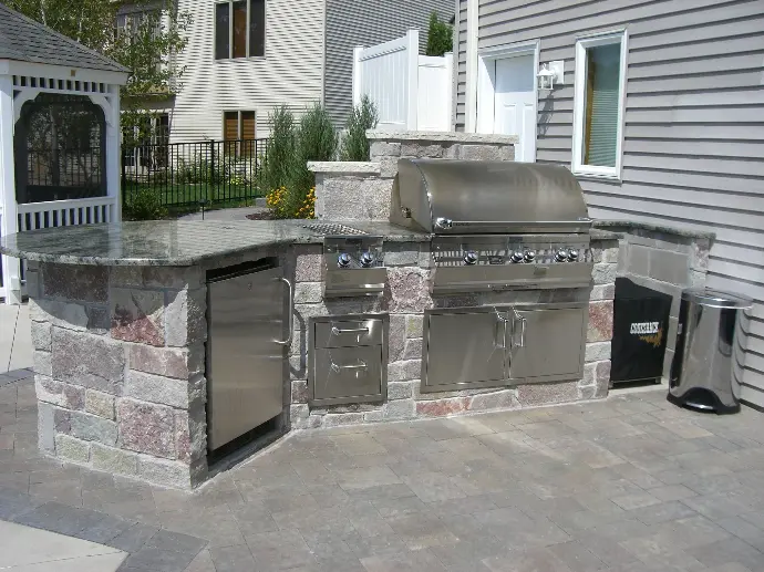 A modern outdoor kitchen featuring a built-in refrigerator and ample counter space, offering convenience for outdoor cooking.