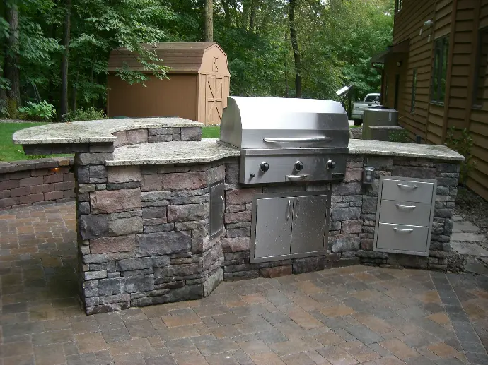 A beautifully designed outdoor kitchen featuring stone countertops, perfect for preparing meals while enjoying the outdoors.