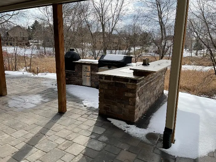 A spacious outdoor kitchen equipped with a built-in grill and adjacent seating area, ideal for backyard barbecues.