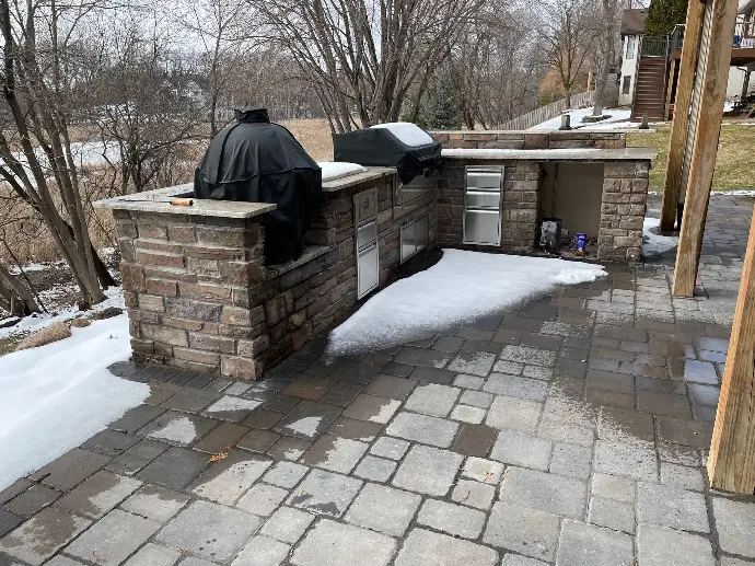 A spacious outdoor kitchen equipped with a built-in grill and adjacent seating area, ideal for backyard barbecues.