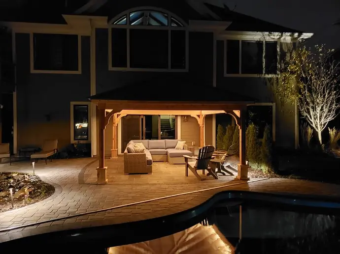 A custom built pergola sits atop this outdoor living area with custom uplighting built under the roof.