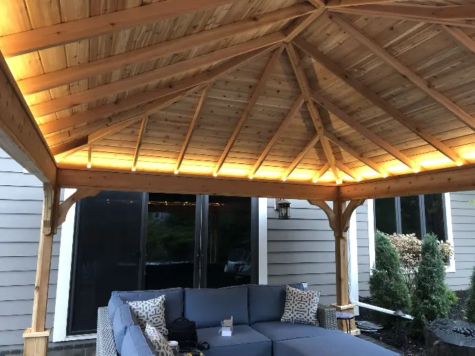 A custom built pergola sits atop this outdoor living area with custom uplighting built under the roof.