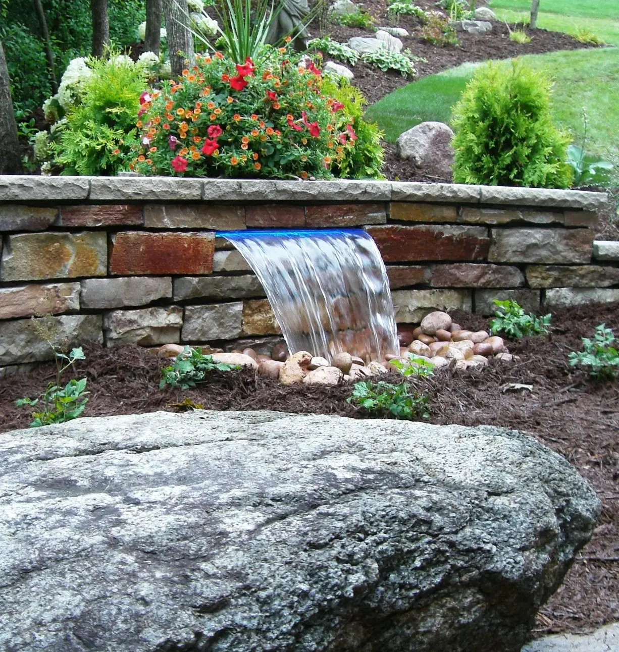 A sleek, modern outdoor fountain made from natural stone, providing a stylish water feature for the garden.