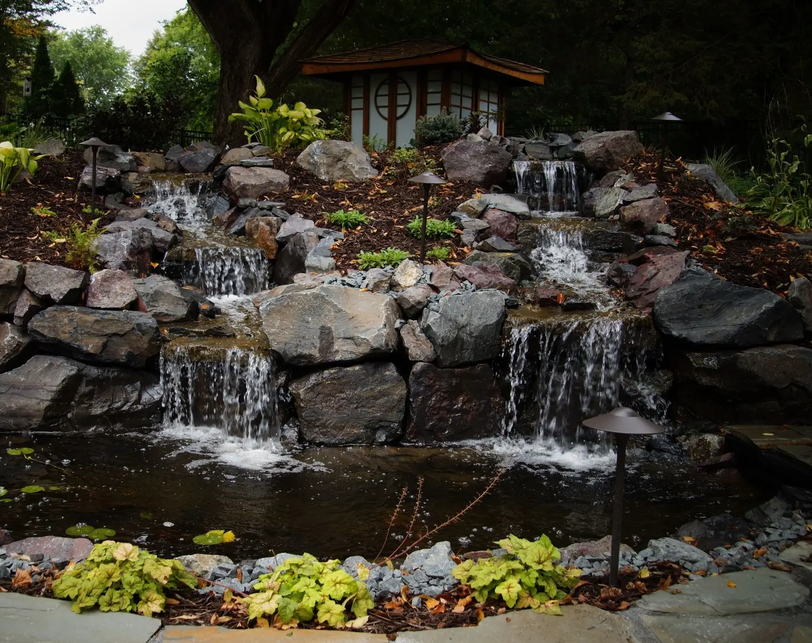 A  tiered waterfall feature using natural rocks, creating a stunning focal point in the backyard with soothing water sounds.